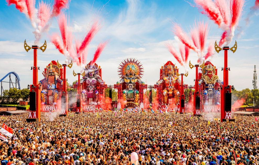 Aerial view of the massive Defqon.1 festival mainstage crowd and production during Power Hour, showing thousands of ravers wearing high-fidelity earplugs, 2026.